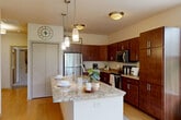 Located at 1300 Post Rd in Fitchburg, Wisconsin, this well-appointed 2-bedroom, 2-bathroom residence offers a thoughtfully designed single-floor layout with generous living space throughout. A welcoming hallway with light hardwood-style flooring leads into the heart of the home.

The open-concept kitchen is a standout feature, showcasing rich dark cabinetry, granite countertops, and a large central island with pendant lighting — ideal for both meal prep and casual dining. Stainless steel appliances complete the modern culinary space, which flows seamlessly into the living and dining areas.

The living room is bright and inviting, with large windows that fill the space with natural light and offer views of the surrounding greenery. A patio door provides direct access to a private balcony overlooking the landscaped community.

The spacious primary bedroom offers comfortable proportions, plush carpeting, and ample closet storage. The second bedroom also features a large window with pleasant outdoor views and a dedicated closet. Both bathrooms are well-finished, with the full bath featuring a walk-in shower, tile flooring, and dark wood vanity cabinetry. Throughout the residence, five closets provide exceptional storage. This home combines functional design with warm, modern finishes in a desirable Fitchburg location.