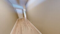 Located at 10 Fieldstone Commons in Tolland, Connecticut, this three-floor townhouse offers a thoughtfully designed layout across generously sized levels. The entry level features an attached garage with a concrete floor and direct interior access, along with an unfinished lower level offering ample storage or flexible-use space with a utility panel and built-in wood cabinetry.

The main living floor showcases a bright, open-concept kitchen and living room combination. The kitchen is appointed with crisp white shaker cabinets, light quartz countertops, stainless steel appliances including a refrigerator, range, and built-in microwave, and a peninsula with an undermount sink. The living area features light hardwood-style flooring, crown molding, a ceiling fan, a classic white-mantled fireplace, and large sliding glass doors that invite natural light and outdoor views.

The upper floor hosts the spacious primary bedroom, complete with plush carpeting, crown molding, a ceiling fan, and a window overlooking the surrounding landscape. The en-suite bathroom includes a soaking tub, separate toilet area, and vanity with stone countertops. A dedicated laundry room and additional closet space round out this level. Warm neutral tones and light hardwood-style flooring flow throughout the hallways and common areas, creating a cohesive and welcoming ambiance.