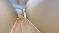 Located at 10 Fieldstone Commons in Tolland, Connecticut, this three-floor townhouse offers a thoughtfully designed layout across generously sized levels. The entry level features an attached garage with a concrete floor and direct interior access, along with an unfinished lower level offering ample storage or flexible-use space with a utility panel and built-in wood cabinetry.

The main living floor showcases a bright, open-concept kitchen and living room combination. The kitchen is appointed with crisp white shaker cabinets, light quartz countertops, stainless steel appliances including a refrigerator, range, and built-in microwave, and a peninsula with an undermount sink. The living area features light hardwood-style flooring, crown molding, a ceiling fan, a classic white-mantled fireplace, and large sliding glass doors that invite natural light and outdoor views.

The upper floor hosts the spacious primary bedroom, complete with plush carpeting, crown molding, a ceiling fan, and a window overlooking the surrounding landscape. The en-suite bathroom includes a soaking tub, separate toilet area, and vanity with stone countertops. A dedicated laundry room and additional closet space round out this level. Warm neutral tones and light hardwood-style flooring flow throughout the hallways and common areas, creating a cohesive and welcoming ambiance.