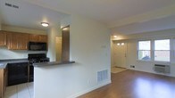 This two-floor residence offers a thoughtfully designed layout that balances functionality and comfort throughout. The main level features an open-concept living area with warm hardwood flooring that extends toward a classic paneled front door, accented by transom windows that invite natural light into the entryway. A half-wall pass-through connects the kitchen to the living space, creating a sense of openness while maintaining a defined cooking area. The kitchen is equipped with wood-toned cabinetry, a dark countertop, and includes a gas range and built-in microwave, providing a practical and efficient workspace. Flush-mount ceiling lighting illuminates both the kitchen and living areas, contributing to a clean, understated aesthetic. Floor vents are integrated throughout, ensuring consistent climate control across the space. The neutral wall tones and white trim create a bright, versatile backdrop suited to a variety of interior styles. With two levels, the home provides ample room for both living and private spaces, making it a well-rounded and functional property for everyday living.
