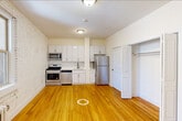 Located at 125 Magnolia Avenue in Jersey City, NJ, this efficiently designed single-floor unit makes excellent use of its compact footprint. Throughout the space, warm-toned hardwood floors create a cohesive and inviting atmosphere, complemented by the striking whitewashed exposed brick walls that lend a distinctive urban character.

The open kitchen is a standout feature, equipped with a full suite of stainless steel appliances including a gas range, dishwasher, microwave, and refrigerator. Crisp white cabinetry with ample storage reaches toward the ceiling, while a classic white subway tile backsplash and clean countertops round out the modern, functional design.

The living area benefits from natural light streaming through a window with views to the exterior, and a cast-iron radiator underscores the building's classic character. A dedicated closet provides convenient built-in storage with a full-width hanging rod.

The bathroom is neatly finished with white subway tile, mosaic floor tile, a pedestal-style vanity, and a round mirror, offering a clean and bright retreat. A stacked washer and dryer unit is conveniently integrated into the space, adding a practical in-unit laundry amenity. Overall, this unit balances historic architectural charm with contemporary updates.