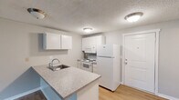 Located at 401 E Magnesium Rd in Spokane, WA, this one-bedroom, one-bathroom unit offers a practical and well-organized single-floor layout. The open-concept kitchen and living area form the heart of the unit, where light wood-style flooring in the kitchen transitions seamlessly into carpeted living space. The kitchen is equipped with white cabinetry, a full suite of white appliances including a refrigerator, electric range, and built-in microwave, along with a peninsula countertop featuring a granite-look surface and an integrated sink — ideal for casual dining or meal prep. The spacious living room is bright and airy, highlighted by a sliding glass door that opens onto a private balcony with outdoor views, and a textured ceiling throughout. Baseboard heating runs along the walls, ensuring comfort year-round. The bedroom offers a cozy carpeted retreat with a window overlooking the outdoors and a wall-mounted AC unit. Two doors from the bedroom lead to a hallway and a dedicated closet with shelving. The bathroom features light wood-style flooring, a full tub-shower combination, a vanity with a countertop sink, and a mirrored medicine cabinet, completing this functional and comfortable unit.