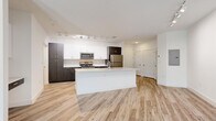 Located at 1659 2nd St in Sarasota, FL, this modern one-bedroom, one-bathroom residence offers a thoughtfully designed open-concept layout with contemporary finishes throughout. Light-toned wood-look flooring flows seamlessly through the main living areas, complemented by crisp white walls and track lighting that enhances the bright, airy ambiance.

The kitchen serves as the centerpiece of the home, featuring a large island with a quartz countertop and an undermount sink, dark espresso cabinetry contrasted by white upper cabinets, and a full suite of stainless steel appliances including a range, microwave, dishwasher, and refrigerator. The kitchen opens directly into the living area, which benefits from a large window that draws in natural light and provides views of the surrounding neighborhood.

The bedroom is a comfortable, carpeted retreat with direct access to the full bathroom. The bathroom is elegantly appointed with large-format stone-look tile flooring, an elongated dual-sink vanity with quartz countertops, and a generous walk-in closet equipped with extensive wire shelving and hanging rods, offering ample storage. Clean lines and a neutral palette throughout create a cohesive, modern aesthetic ideal for Sarasota living.
