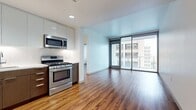 This contemporary 640 square foot apartment in Los Angeles offers a blend of style and functionality. The open-concept design maximizes the use of space, creating a seamless flow between the living areas. The apartment features sleek hardwood flooring throughout, enhancing the modern aesthetic.

The kitchen is a highlight, boasting stainless steel appliances, including a side-by-side refrigerator, oven, and built-in microwave. The two-tone cabinetry, with white upper cabinets and wood-finish lower cabinets, provides ample storage and a sophisticated look. A white tile backsplash and under-cabinet lighting add to the kitchen's polished appearance.

The spacious 150 square foot bedroom offers a private retreat with large windows that allow natural light to flood the space. The bathroom features a modern vanity with a large mirror and built-in storage. A walk-in closet with custom shelving provides generous storage options.

Large windows throughout the apartment offer city views and create a bright, airy atmosphere. The living room includes sliding glass doors leading to a balcony, perfect for enjoying the outdoors. The apartment's neutral color palette and clean lines contribute to its contemporary feel, making it an ideal urban dwelling in the heart of Los Angeles.