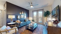 Located at 2818 Cullman Ave in Charlotte's 28206 neighborhood, this single-floor residence offers a well-designed layout with contemporary finishes throughout. The living room makes a striking impression with a bold navy accent wall, a tufted teal sofa, ceiling fan, and French doors that open onto a private balcony, flooding the space with natural light and offering views of surrounding greenery. A gallery wall arrangement adds a curated, artistic touch to the room's ambiance. The kitchen is equipped with stainless steel appliances, granite countertops, a central island with pendant lighting, and a two-tone cabinet scheme featuring white lower and gray upper cabinetry — all complemented by wood-look flooring that flows throughout the common areas. An entry nook with a wall-mounted hook rail provides a practical transition space. Both bedrooms are bright and inviting, each featuring ceiling fans, large windows with tree-lined views, and plush carpeting. The primary bedroom showcases a warm accent wall and vibrant artwork, while the second bedroom features a light, airy palette with pendant lighting. Each bathroom is finished with granite vanities, wood-look tile flooring, and direct access to dedicated walk-in closets, offering generous storage and functionality.