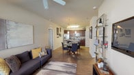 This single-story residence is designed with an open-concept layout that seamlessly connects the living, dining, and kitchen areas into one cohesive and functional space. The living room features wood-style flooring, a ceiling fan, and large windows that allow natural light to fill the room. The adjacent dining area flows directly into the kitchen, which is equipped with rich dark-wood cabinetry, stainless steel appliances including a refrigerator, microwave, and range, as well as a center island with a dark countertop and pendant lighting overhead. A dedicated in-unit laundry area provides added convenience with a full-size washer and dryer.

The bedrooms are carpeted and well-lit by natural light from sizable windows dressed with blinds and drapes. Each room offers a comfortable and quiet retreat, with at least one bedroom featuring a walk-in closet outfitted with wire shelving and hanging rods. The bathroom includes a dark-wood vanity, tile flooring, and a glass-enclosed walk-in shower alongside a linen closet for additional storage. Overall, the space presents a clean, modern aesthetic with practical finishes throughout.