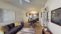 This single-story residence is designed with an open-concept layout that seamlessly connects the living, dining, and kitchen areas into one cohesive and functional space. The living room features wood-style flooring, a ceiling fan, and large windows that allow natural light to fill the room. The adjacent dining area flows directly into the kitchen, which is equipped with rich dark-wood cabinetry, stainless steel appliances including a refrigerator, microwave, and range, as well as a center island with a dark countertop and pendant lighting overhead. A dedicated in-unit laundry area provides added convenience with a full-size washer and dryer.

The bedrooms are carpeted and well-lit by natural light from sizable windows dressed with blinds and drapes. Each room offers a comfortable and quiet retreat, with at least one bedroom featuring a walk-in closet outfitted with wire shelving and hanging rods. The bathroom includes a dark-wood vanity, tile flooring, and a glass-enclosed walk-in shower alongside a linen closet for additional storage. Overall, the space presents a clean, modern aesthetic with practical finishes throughout.