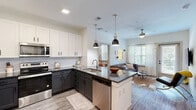 Located at 13060 Clemson Blvd in Seneca, SC, this thoughtfully designed 2-bedroom, 3-bathroom residence offers a efficient and modern single-floor layout. The open-concept kitchen is a standout feature, boasting two-tone cabinetry with crisp white upper cabinets and dark lower cabinets, a subway tile backsplash, granite countertops, stainless steel appliances, and a central island with pendant lighting. The kitchen flows seamlessly into the living room, which features wood-look flooring, a ceiling fan, and a glass door leading to a private balcony with natural light streaming through large windows. Each bedroom is well-appointed with natural light, wood-look flooring, and windows offering outdoor views. The three bathrooms are consistently finished with granite-topped dark vanities, large mirrors, and wood-look tile flooring — two of which feature tub/shower combinations. A dedicated laundry room with full-size washer and dryer adds everyday convenience. Throughout the residence, clean white walls, recessed lighting, and cohesive hard-surface flooring create a bright, contemporary ambiance that is both functional and inviting.