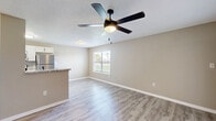 Located at 2109 Polo Club Dr in Kissimmee, Florida, this single-floor, one-bedroom, one-bathroom home offers a well-designed layout with modern finishes throughout. Light gray luxury vinyl plank flooring runs seamlessly across the entire space, complemented by neutral warm-toned walls, crisp white baseboards, and textured ceilings.

The heart of the home is an open-concept living, dining, and kitchen area that maximizes the use of space. The kitchen is a standout feature, boasting white shaker-style cabinetry, granite countertops, stainless steel appliances — including a refrigerator and dishwasher — and a peninsula that doubles as a breakfast bar. Ceiling fans with integrated lighting are present in both the living area and bedroom, ensuring comfort throughout.

The bedroom is a comfortable, well-proportioned retreat featuring a ceiling fan, a window that brings in natural light, a sliding glass door opening to one of two patios, and access to two closets. The bathroom is cleanly appointed with a white vanity, granite countertop, a round mirror with a matte black frame, matching black fixtures, and a tub/shower combination. Additional conveniences include an in-unit laundry area and a hallway connecting the main spaces. Two patio areas provide outdoor access, ideal for enjoying the Florida climate.