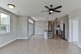Located at 1441–1447 Commerce Dr in Decatur, GA, this single-floor unit offers a thoughtfully designed open-concept layout with contemporary finishes. Light wood-tone flooring runs throughout the main living areas, complementing neutral wall tones and crisp white baseboards to create a clean, modern aesthetic.

The living and dining area is generously sized, bathed in natural light from multiple large windows that frame views of surrounding greenery. Ceiling fans are installed throughout, enhancing comfort and airflow. The kitchen is a standout feature, equipped with stainless steel appliances including a range, microwave, and French door refrigerator. Light wood-grain cabinetry extends to the ceiling, paired with dark countertops, a subway tile backsplash, and a central island with built-in wine storage and pendant lighting above.

A hallway connects the main living space to the private quarters, featuring built-in wall niches for added character. Bedrooms are carpeted and well-lit with natural light from standard windows. The primary bathroom includes a dark-countered vanity, tile flooring, and access to a walk-in closet. A secondary bathroom features a soaking tub with a tiled surround and chrome fixtures, providing a clean and functional design throughout.