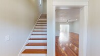 Located at 204 Potters Bluff Dr in Panama City Beach, FL, this three-story home offers a well-organized layout across three distinct floor levels. The ground floor provides the most expansive footprint, housing the attached garage with concrete flooring, a covered patio area with brick pavers, and exterior staircase access. The main living level features rich hardwood flooring throughout the open-concept kitchen and living areas. The kitchen is equipped with stainless steel appliances, a center island with white countertops, and contemporary cabinetry, all illuminated by recessed lighting and a pendant fixture. The adjacent living room benefits from a ceiling fan and natural light through slatted blinds. Upper floors contain the three bedrooms, each finished with neutral carpet and ceiling fans. The generously sized primary bedroom includes a private en-suite bathroom appointed with a double-sink vanity, white cabinetry, tile flooring, and a soaking tub framed in mosaic tile. Additional bathrooms feature tiled tub-shower combinations. Bedrooms include closets with built-in shelving. Multiple staircases connect the levels, and the home's clean white trim and neutral wall tones create a cohesive, light-filled atmosphere throughout.