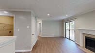 Located at 100 Calibre Lake Pkwy SE in Smyrna, Georgia, this one-bedroom, one-bathroom residence offers a well-organized single-floor layout with a thoughtful mix of finishes and functional spaces. The combined kitchen and living room serves as the heart of the home, where warm hardwood-style flooring flows throughout. The kitchen is equipped with stainless steel appliances — including a gas range and refrigerator — honey-toned wood cabinetry, light granite-style countertops, and a peninsula that provides additional prep space and a natural divider between the kitchen and living area. Crown molding adds a polished architectural detail throughout. The living room is highlighted by a classic wood-burning fireplace framed by a white mantel with tile surround, a large window that draws in natural light, and sliding glass doors that open onto a private balcony overlooking lush, mature trees. The bedroom is carpeted for comfort, features a ceiling fan, a window with wooded views, and direct access to a dedicated closet. The bathroom includes a full tiled tub-and-shower combination. A utility room rounds out the layout, adding practical storage and functionality. The overall ambiance is clean, neutral, and move-in ready.