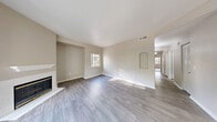 Located at 770 W Lone Mountain Rd in North Las Vegas, NV, this single-floor, 3-bedroom, 2-bathroom residence offers a well-designed layout with a comfortable blend of functionality and style. The open-concept living, dining, and kitchen area forms the heart of the home, highlighted by wood-look plank flooring, neutral warm-toned walls, and a classic fireplace with a white mantle. Large sliding glass doors flood the living room with natural light and provide direct access to a private balcony with outdoor views. The kitchen is equipped with stainless steel appliances — including a gas range, built-in microwave, refrigerator, and dishwasher — complemented by white shaker cabinetry and light stone countertops. The adjacent dining area features a ceiling fan and a window overlooking the exterior. The three bedrooms are carpeted for comfort, each with mirrored closet doors and windows allowing natural light. The primary bedroom includes a ceiling fan and a generously sized closet. Both bathrooms feature wood-look tile flooring, a tub-shower combination, and a single-sink vanity with stone-style countertops. Additional highlights include an in-unit laundry area, a utility room, and an abundance of closet storage throughout.