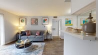 This efficiently designed single-story, 1-bedroom, 1-bathroom home offers a thoughtful open-concept layout that maximizes every square foot. Wood-style flooring flows throughout, lending warmth and continuity across all living areas.

The living room serves as the heart of the home, highlighted by a white brick fireplace, a sliding glass door that invites natural light and outdoor views, and ample space for comfortable seating. It connects seamlessly to the dining area and kitchen, creating an ideal open-plan living environment.

The galley-style kitchen is well-equipped with black appliances, white cabinetry, a grey subway tile backsplash, and light stone countertops that extend to a breakfast bar peninsula — a practical divider between the kitchen and dining space.

The bedroom is a comfortable retreat featuring wood-style flooring, a ceiling fan, and a window that provides natural light. A dedicated closet offers convenient storage. The full bathroom includes a tub-shower combination with clean white tile surround.

An in-unit laundry area accommodates a full-size washer, adding everyday convenience. The home's neutral grey-white palette and modern finishes throughout create a clean, cohesive aesthetic well-suited for contemporary living.