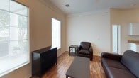 This single-floor residence offers a well-organized and functional layout across several distinct living areas. The galley-style kitchen is outfitted with white cabinetry, laminate countertops, and a full suite of white appliances including a range, built-in microwave, and refrigerator. Wood-look flooring runs the length of the kitchen, adding warmth to the space, while a double-basin sink provides added convenience.

The living room features the same wood-look flooring, crown molding, and a window that brings in natural light, creating a comfortable and inviting area. Adjacent to the kitchen, the dining area accommodates a four-seat table and is finished with crown molding and recessed lighting.

The space includes multiple bedrooms, each carpeted and equipped with a ceiling fan. Several rooms feature windows with blinds that allow for natural light and outdoor views, and each room includes a desk and storage furnishings, making them well-suited for study or work. One bedroom stands out with a distinctive arched window that adds architectural character.

Two full bathrooms serve the space, each featuring a tub-shower combination with chrome fixtures. One bathroom includes a vanity with a single-basin sink, a large mirror with overhead lighting, and tile flooring, while the other maintains a similarly clean, functional design throughout.