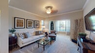 This single-floor residence offers a thoughtfully designed layout with a cohesive neutral palette and consistent architectural detailing throughout. Crown molding accents the living room, which features plush carpet, a ceiling fan with light fixture, and multiple windows allowing natural light to fill the space. An open sightline connects the living area to a sunlit sitting nook framed by sheer curtains and shuttered windows, creating an airy extension of the main gathering space.

The dining area is defined by an arched architectural niche, adding character to the room. Wood-look flooring transitions from the entryway into this space, which comfortably accommodates a full dining set.

The kitchen is equipped with white cabinetry, granite-look countertops, stainless steel appliances, and wood-look flooring, offering a clean and functional workspace.

The primary bathroom features a lengthy dual-vanity with granite countertops, white cabinetry, hardwood flooring, and well-lit mirrors, delivering a refined and practical layout.

Both bedrooms are carpeted and well-lit by large windows with blinds and curtain panels. One bedroom includes a walk-in closet, while the other offers closet access alongside a private exit. The overall ambiance is warm, cohesive, and move-in ready.