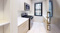 Located in the heart of Midtown Manhattan, this 2-bedroom, 2-bathroom residence at 313 W 57th St offers a well-appointed layout with consistent design details throughout. Rich parquet wood flooring runs across the living areas and bedrooms, lending warmth and a classic New York character to the space. The open living area is generously proportioned, bathed in natural light through large black-framed windows that frame city views of the surrounding Midtown skyline and neighboring buildings.

The kitchen has been thoughtfully renovated, featuring light wood cabinetry with gold hardware, crisp white countertops, and a full suite of stainless steel appliances including a gas range and over-the-range microwave. Light tile flooring and a window provide brightness and ventilation.

Both bedrooms are well-sized with parquet flooring, ample natural light, and city-facing windows. One bedroom includes a built-in closet with sliding doors for convenient storage.

The two bathrooms are both modernized, each featuring sleek floating vanities, glass-enclosed shower/tub combinations, and elegant tilework. One bathroom showcases marble-style white tile, while the second features rich, dark wood-toned wall panels, offering a contrast of refined styles. Recessed lighting completes the polished, contemporary finish throughout.