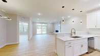 Located at 215 S Westmore Ave in Lombard, IL, this thoughtfully designed one-bedroom, one-bathroom residence offers a bright and modern living experience across a generous single floor. Light-toned hardwood flooring runs throughout, unifying the open-concept layout with a clean, contemporary aesthetic.

The kitchen is a standout feature, showcasing white shaker cabinetry with gold hardware, a marble-look quartz peninsula, stainless steel appliances, and stylish pendant lighting. It flows seamlessly into the expansive living room, which is anchored by a dramatic floor-to-ceiling marble-tile accent wall housing a built-in electric fireplace. Large windows and a sliding glass door flood the living area with natural light and provide access to an outdoor balcony with green views.

The spacious primary bedroom is appointed with crown molding, a modern ring chandelier, ambient LED cove lighting, and a large window overlooking the outdoors. It connects to a generously sized walk-in closet with dual shelving walls and dedicated laundry with a stacked washer and dryer unit nearby.

The bathroom features marble-look tile flooring, a navy vanity with white countertop, an illuminated mirror, and a full tub-shower combination. Crown molding and recessed lighting are featured throughout, adding a polished, upscale feel to every room.