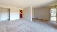 Located at 2101 Prior Rd in Wilmington, Delaware, this single-floor residence offers a straightforward and functional layout designed for comfortable everyday living. The spacious living area is finished with plush wall-to-wall carpeting and neutral-toned walls, creating a calm and inviting atmosphere. A large sliding glass door floods the room with natural light and provides views of the surrounding greenery, while vertical blinds offer privacy and light control. A closet with bifold doors adds convenient built-in storage to the living space. The layout opens toward a defined kitchen area, which features warm wood-toned cabinetry, dark granite-style countertops, a stainless steel sink, and white appliances including a gas range with an over-the-range microwave. The kitchen is well-appointed for everyday meal preparation. The bathroom is clean and practical, complete with a full soaking tub and shower combination, a toilet, tiled flooring in an earthy pattern, and an overhead medicine cabinet for storage. Throughout the residence, the neutral color palette and consistent finishes contribute to a cohesive and move-in-ready aesthetic. The 3D model reveals a well-organized floor plan with clearly defined rooms and accessible interior doors connecting each space efficiently.