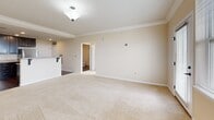 Located at 200 Adams Dr in McKees Rocks, PA, this well-appointed one-bedroom, one-bathroom unit offers a thoughtfully designed single-floor layout. The open-concept kitchen and living area serves as the heart of the home, where rich dark cabinetry contrasts beautifully with light granite countertops and stainless steel appliances, including a refrigerator, range, and microwave. A peninsula with bar seating provides both additional prep space and a casual dining option. Hardwood-style flooring anchors the kitchen, while plush carpeting extends into the living room, which features crown molding and access to a private balcony with scenic views of the surrounding landscape. The bedroom is a comfortable retreat, bathed in natural light through large windows that frame lush tree and open-sky views, with soft carpet underfoot. The bathroom is finished with dark cabinetry, a vanity with a light countertop, and a walk-in shower with a built-in bench. A hallway and dedicated closet provide practical storage solutions. Throughout the unit, neutral warm tones, recessed lighting, and clean white trim create a bright, cohesive ambiance.