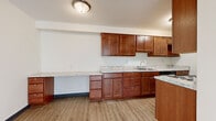 Located at 1776 Saint Clair Ave in Saint Paul, Minnesota, this two-bedroom, one-bathroom unit offers a thoughtfully organized single-floor layout with a comfortable sense of space throughout. The kitchen is a standout feature, showcasing rich warm-toned cabinetry, light granite-style countertops, a built-in desk or extended counter area, and hardwood-style vinyl flooring. Appliances including a stove and refrigerator are seamlessly integrated alongside ample upper and lower cabinet storage. The kitchen opens toward a hallway and closet area, creating an efficient flow into the rest of the unit. The living room is bright and airy, benefiting from multiple windows that invite natural light and offer views of the surrounding neighborhood. It features hardwood-style flooring, a wall-mounted AC unit, and baseboard heating. The primary bedroom is generously sized, carpeted for comfort, and includes a ceiling fan, sliding closet doors, and access to an additional storage closet. The second bedroom is similarly carpeted with a ceiling fan and window. The full bathroom is appointed with warm-toned tile flooring, a tub-shower combination with white tile surround, a vanity with storage cabinetry, and a small window for ventilation. A hallway connects all rooms, lending the unit a cohesive and functional layout.