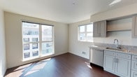 Located in Seattle's vibrant West Seattle neighborhood, Unit 609 at 4505 42nd Ave SW is a thoughtfully designed single-floor residence that blends modern finishes with an abundance of natural light. Rich, dark hardwood flooring flows throughout the main living and kitchen areas, creating a warm and cohesive aesthetic against the clean, neutral-toned walls.

The kitchen is well-appointed with gray shaker-style cabinetry, granite countertops, and a full suite of stainless steel appliances including a refrigerator, range, microwave, and dishwasher. Large windows bathe the kitchen and adjoining living area in sunlight while framing views of the surrounding Seattle cityscape.

The open living area is generously sized, with multiple windows that invite natural light and offer elevated neighborhood views. The layout provides a seamless connection between the kitchen and living space, making it ideal for both everyday living and entertaining.

The bedroom features plush wall-to-wall carpeting and a bright window with sweeping outdoor views, creating a calm and restful retreat. Neutral tones throughout the unit contribute to a clean, move-in ready atmosphere. The overall ambiance of this residence is modern, airy, and bright, well-suited for those seeking contemporary urban living in Seattle.