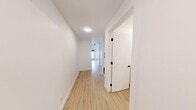 This thoughtfully designed one-bedroom, one-bathroom unit in Calgary, AB offers a clean, modern aesthetic throughout its efficiently organized single-floor layout. Light-toned luxury vinyl plank flooring runs continuously throughout the space, creating a warm and cohesive look that complements the crisp white walls and bright white trim.

A welcoming hallway serves as the central spine of the unit, connecting all rooms and providing convenient access to the stacked in-unit washer and dryer—a practical feature that adds everyday convenience. The bedroom is a cozy yet functional space, featuring black-framed windows that bring in natural light while adding a contemporary design contrast against the white walls. A sliding closet door contributes to the room's clean, uncluttered feel.

The bathroom is finished with white subway-style wall tiles, a full soaker tub with an overhead shower, chrome fixtures, and open built-in shelving for added storage. The all-white palette creates a bright, clean atmosphere.

The unit's layout, as revealed in the dollhouse view, makes efficient use of every square foot, with each area logically connected. The consistent use of light flooring, white walls, and black accents throughout lends a cohesive, modern character to the entire space—ideal for those seeking a clean, minimalist home in Calgary.