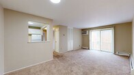 Located at 12205 Valley Lane Dr in Garfield Heights, Ohio, this two-bedroom, two-bathroom residence offers a practical and well-organized single-floor layout. The living room is the heart of the home, featuring wall-to-wall carpeting, a baseboard heating system, and a sliding glass door dressed with vertical blinds that floods the space with natural light and provides access to an outdoor balcony. A wall-mounted air conditioning unit ensures year-round comfort. The kitchen connects to the living area via a convenient pass-through window, and is equipped with white cabinetry and a refrigerator, creating an open and communicative flow between spaces. The primary bedroom is generously sized, offering a carpeted floor, a dedicated closet, and a private en-suite bathroom, providing a comfortable and self-contained retreat. The second bedroom is also carpeted and benefits from a large window that brings in natural light. Both bathrooms share a consistent design aesthetic, featuring white vanities with under-sink storage, mirrored medicine cabinets, and a combination tub-shower. One bathroom is accented by warm yellow tile along the walls, adding a distinct character. Throughout, the neutral beige tones and clean white trim create a calm, cohesive ambiance.