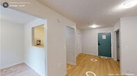 Located at 2504 NC-54 in Durham, NC, this single-floor unit offers a practical and efficiently designed layout comprising a living room, kitchen, and closet. Light-toned hardwood flooring runs throughout the space, contributing to a bright and cohesive feel. The living area features white walls, a textured ceiling, and a window that allows natural light to filter in, creating an open and airy atmosphere. A wall-unit HVAC provides climate control, and multiple electrical outlets are positioned throughout for added convenience. A dedicated closet with a built-in hanging rod offers practical storage. The kitchen is well-appointed with white shaker-style cabinetry, marble-patterned countertops, an under-cabinet range hood, a white electric range, a full-size refrigerator, and a stainless steel sink. A pass-through window connects the kitchen to the living area, enhancing the sense of openness between the two spaces. The overall design is clean and minimal, with a consistent neutral color scheme that makes the unit feel bright and easy to personalize. This space is ideally suited for those seeking a straightforward, low-maintenance living environment in the Durham area.