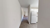 Located in Naugatuck, CT, this single-floor residence offers a well-organized layout across two bedrooms, one bathroom, and a combined kitchen and living area. The spacious living room is anchored by plush wall-to-wall carpeting, a textured ceiling, and a large sliding glass door that opens to a balcony, filling the room with natural light and providing outdoor views. Baseboard heating runs throughout, ensuring consistent warmth across the space.

The galley-style kitchen is efficiently designed with white shaker cabinets, granite-look countertops, a stainless steel sink, and white appliances including a stove and refrigerator. Wood-look flooring adds a clean, modern touch to this functional cooking space.

Both bedrooms are carpeted and neutrally toned, offering a quiet and comfortable atmosphere. The primary bedroom features a bi-fold closet, while the second bedroom benefits from a bright window with views of the surrounding area and baseboard heating along the walls.

The bathroom is clean and bright, featuring a white vanity, tiled tub-shower combination, wood-look flooring, and a window for natural ventilation. The overall aesthetic throughout the home is light, neutral, and move-in ready.