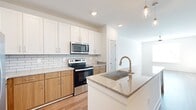 Located at 5141 Stone Mountain Hwy in Stone Mountain, GA, this well-designed one-bedroom, one-bathroom residence offers a thoughtful layout across a single floor. The open-concept kitchen serves as a central highlight, showcasing a large granite-topped island with an undermount sink, pendant lighting, and a striking combination of white upper shaker cabinets and warm wood-toned lower cabinetry. A classic subway tile backsplash complements the full suite of stainless steel appliances, including a refrigerator with ice maker, electric range with over-the-range microwave, and dishwasher. Light hardwood flooring extends throughout the main living areas, enhancing the bright, airy atmosphere. The living room is generously proportioned with large windows that invite natural light and outdoor views, along with a ceiling fan overhead. The bedroom features plush carpeting, a ceiling fan, and a window with natural light. It connects directly to the full bathroom, which includes a granite vanity, wood-toned cabinetry, a frameless glass walk-in shower with tile surround, and hardwood flooring. A dedicated walk-in closet with wire shelving provides practical storage. A hallway completes the functional flow of this clean, contemporary residence.