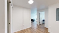 This single-floor, 3-bedroom, 2-bathroom home offers a clean and functional layout designed for comfortable living. Light wood flooring runs consistently throughout the space, complemented by crisp white walls that create a bright, cohesive atmosphere.

The open living room is a welcoming space featuring a wide bank of windows that invite natural light and provide views of the surrounding neighborhood. The kitchen is well-appointed with white shaker cabinetry, white quartz countertops, stainless steel appliances including a range, microwave, and dishwasher, and light wood flooring that continues seamlessly from the living area.

Each of the three bedrooms is thoughtfully sized, with the spacious primary bedroom offering a comfortable retreat. The bedrooms feature closets for ample storage. The two bathrooms each include a full bathtub and shower combination with classic tile surrounds — one featuring warm peach tiling with orange accents, and the other with a similar palette accented by deep red tile trim — alongside white vanities with quartz countertops.

A dedicated laundry room stands out with its generous white cabinetry, bold blue countertops, a utility sink, and washer and dryer hookups, providing excellent functionality. Two additional closets round out the storage options throughout this well-designed home.