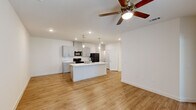 Located at 4663 Joor Rd in Baton Rouge, LA, this single-story 2-bedroom, 1-bathroom home offers a thoughtfully designed layout with modern finishes throughout. The open-concept living and kitchen area serves as the heart of the home, featuring warm luxury vinyl plank flooring, recessed lighting, and a ceiling fan that enhances the airy atmosphere. The kitchen is a standout, showcasing gray shaker-style cabinetry, a white subway tile backsplash, and a generous center island topped with a striking marble-look quartz countertop complete with an integrated sink. Pendant lights hang above the island, adding a stylish focal point, while black appliances including a range, microwave, and refrigerator provide a bold contrast to the light cabinetry. The bedrooms are carpeted for comfort, each equipped with ceiling fans and natural light from windows. The primary bedroom includes a walk-in closet with built-in shelving. The bathroom continues the home's clean aesthetic with gray cabinetry, a marble-look quartz vanity top, and wood-look flooring. Clean white walls and consistent finishes throughout give the space a fresh, move-in-ready feel.