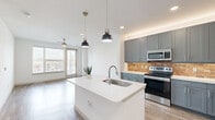 Located at 2902 Race St in Fort Worth, TX, this thoughtfully designed one-bedroom, one-bathroom residence offers a comfortable and modern living experience across a single floor. The open-concept layout seamlessly connects the kitchen and living room, creating an inviting, airy atmosphere filled with natural light from large windows. The kitchen is a standout feature, boasting a central island with a white quartz countertop and undermount sink, gray shaker-style cabinetry, a warm brick tile backsplash, and a full suite of stainless steel appliances, including a French door refrigerator, range, microwave, and dishwasher. Stylish pendant lights anchor the island, adding a contemporary touch. The living area extends toward large windows and a glass door that brings in abundant daylight, complemented by wood-look flooring and a ceiling fan. The bedroom is carpeted for comfort, features its own ceiling fan, a window with outdoor views, and leads directly to a generously sized walk-in closet outfitted with dual-level wire shelving. The bathroom is elegantly appointed with blue-gray cabinetry, white quartz countertops, a wide vanity mirror, and a marble-tiled tub and shower surround, with wood-look flooring tying the space together cohesively.