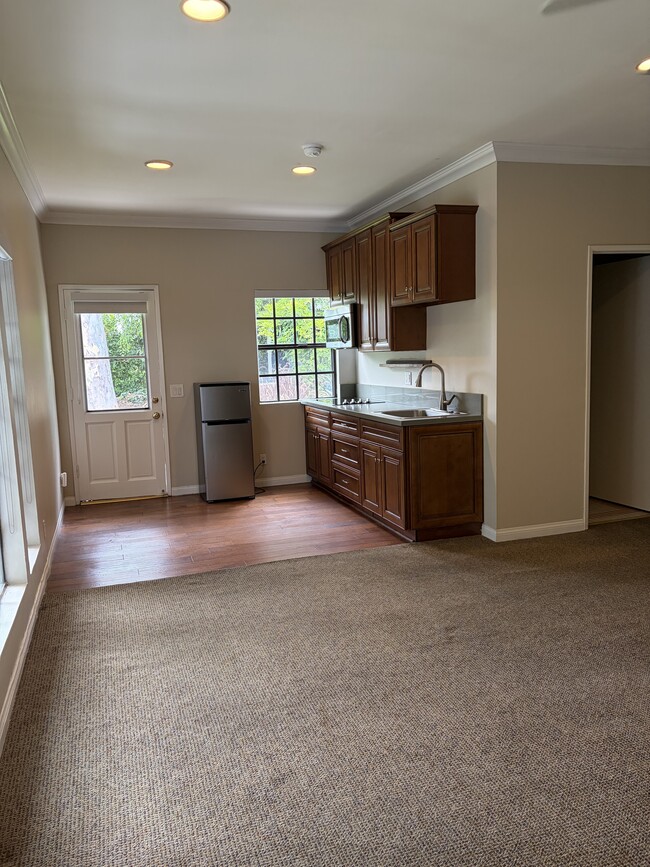 Wall kitchen with wood cabinets. Microwave, fridge and stovetop. Space fir small table - 665 Rim Rd