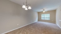 Located at 201 Kroger Drive in Richmond Hill, Georgia, this single-floor residence offers a well-organized layout designed for comfortable everyday living. The kitchen serves as a central hub, featuring rich dark wood cabinetry, white appliances including a range, microwave, and refrigerator, and a peninsula with a sink that opens toward the living and dining areas. Stone-pattern tile flooring runs throughout the kitchen and bathrooms, providing a durable and visually appealing contrast to the plush carpet found in the living spaces and bedrooms. The dining area benefits from an elegant chandelier overhead and connects seamlessly to the kitchen, creating an open and functional flow. Multiple bedrooms are carpeted and well-proportioned, each equipped with a ceiling fan with light kit and a window that allows natural light to filter in. Closet access is provided in the bedrooms, adding practical storage. The bathrooms are finished with the same stone-pattern tile flooring, dark wood vanities with light countertops, large mirrors, and wall-mounted lighting. One bathroom includes a tub-shower combination, while another features a standalone vanity and toilet. Neutral warm beige tones throughout the unit create a cohesive, inviting ambiance suited for a variety of furnishing styles.