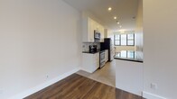 This single-floor unit offers a thoughtfully designed layout with a clean, contemporary aesthetic. Rich hardwood flooring flows throughout the main living areas and bedrooms, providing warmth and continuity across the space. Multiple rooms feature large black-framed windows that frame views of surrounding urban buildings, allowing generous natural light to fill the interiors.

The kitchen is well-equipped and finished to a high standard, featuring white shaker-style cabinetry extending to the ceiling, dark granite countertops, a marble-style backsplash, and a full suite of stainless steel appliances including a refrigerator, dishwasher, stove, and microwave. Recessed lighting illuminates the kitchen and adjacent areas effectively.

The living and sleeping areas are bright and open, with neutral walls, clean white baseboards, and ample closet space provided by double-door built-in closets. Recessed ceiling lights complement the natural light from the windows.

The bathroom is finished with large-format tile flooring and wall tile, a white vanity with drawer storage, an integrated sink, a mirrored medicine cabinet, and a shower-tub combination. The overall design of the unit is modern, neutral, and move-in ready.