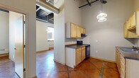 Located at 10 Fourth St E in downtown Saint Paul, Minnesota, this unit offers a distinctive urban loft character across a single floor with two bedrooms and one bathroom. The space is defined by its industrial design elements, including exposed ductwork and structural elements overhead that lend an authentic loft ambiance throughout.

The kitchen features light wood cabinetry, dark countertops, and a black range, with pendant lighting hanging from above. An open sightline connects the kitchen to the adjacent living area, enhancing the sense of flow. The tile flooring—laid in a diagonal pattern with rich terracotta tones—runs consistently throughout the unit, providing a warm and cohesive visual foundation.

The two bedrooms are straightforward and functional. The primary bedroom benefits from a large window framing views of the downtown Saint Paul skyline, with a baseboard heating unit below and ample wall space. The second bedroom offers a sliding closet and neutral walls, suitable for a variety of uses. The bathroom includes a light wood vanity with a large mirror, a toilet, and the same tile flooring found throughout the unit.

Textured walls and high ceilings contribute to the loft feel, while the urban setting provides a vibrant backdrop. This unit suits those seeking an industrial-style space in the heart of downtown Saint Paul.