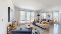 Located at 305 Prine Pl in Charlotte, NC, this single-floor residence offers a thoughtfully designed layout that balances comfort and functionality. The expansive living room is a standout feature, bathed in natural light streaming through a bank of large windows dressed with sheer curtains and blinds. The open layout accommodates generous seating arrangements and flows seamlessly into a dining area, which includes direct access to a private balcony through a glass door. The kitchen is well-equipped with white shaker cabinetry, granite countertops, a teal-accented island with pendant lighting, a tile backsplash, and stainless steel appliances. The primary bedroom is a serene retreat with a ceiling fan, plush carpeting, and a large window with outdoor views. A secondary bedroom features its own walk-in closet, offering practical storage. A dedicated home office nook provides a quiet workspace complete with hardwood-style flooring. The bathroom is finished with a granite-topped vanity, white cabinetry with black hardware, a large mirror, and durable wood-look flooring. Throughout the home, a neutral color palette and contemporary finishes create a cohesive, modern aesthetic.