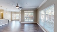 This thoughtfully designed 2-bedroom, 1-bathroom residence offers a comfortable and cohesive living experience across a single floor. The living room is a standout space, featuring rich hardwood-style flooring, elegant crown molding, and a ceiling fan. Multiple large windows with white plantation-style blinds flood the room with natural light, while an angled bay-style wall adds architectural character and outdoor views of the surrounding greenery.

The kitchen is well-equipped with crisp white shaker cabinetry, light quartz countertops, stainless steel appliances including a French door refrigerator, electric range, and microwave, as well as a decorative arabesque tile backsplash that adds a stylish touch.

The generously sized primary bedroom continues the hardwood-style flooring and crown molding, complemented by a ceiling fan and a natural light-filled window. It connects to a spacious walk-in closet outfitted with wire shelving and organizational racks. The second bedroom mirrors similar finishes with its own ceiling fan and window.

The bathroom features a full soaking tub with a tiled surround, a wide vanity with white cabinetry and a bright mirror, and coordinating hardwood-style flooring. A dedicated laundry room houses a full-size top-loading washer and dryer with overhead shelving for added storage convenience.