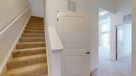 This two-story residence is designed with an open and functional layout that connects living spaces seamlessly across both levels. The main living area is a standout feature, boasting soaring double-height ceilings and a dramatic floor-to-ceiling window wall with a sliding glass door that opens to a private balcony, flooding the space with abundant natural light and offering views of the surrounding neighborhood.

The kitchen is well-appointed with rich, dark-stained wood cabinetry, granite countertops, stainless steel appliances including a range, microwave, and refrigerator, and a central island that provides additional workspace and seating. Hardwood-style flooring extends throughout the kitchen and main living areas, transitioning to plush neutral carpeting in the bedrooms and living room.

The bedrooms are generously proportioned, featuring carpeted floors, ample closet space, and access to bathrooms finished with granite-topped vanities, dark wood cabinetry, tile flooring, and glass-enclosed showers. A secondary bathroom echoes the same quality finishes with a clean, functional layout. A carpeted staircase with a white-panel interior door connects the two floors, completing this well-designed multi-level home.