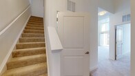 This two-story residence is designed with an open and functional layout that connects living spaces seamlessly across both levels. The main living area is a standout feature, boasting soaring double-height ceilings and a dramatic floor-to-ceiling window wall with a sliding glass door that opens to a private balcony, flooding the space with abundant natural light and offering views of the surrounding neighborhood.

The kitchen is well-appointed with rich, dark-stained wood cabinetry, granite countertops, stainless steel appliances including a range, microwave, and refrigerator, and a central island that provides additional workspace and seating. Hardwood-style flooring extends throughout the kitchen and main living areas, transitioning to plush neutral carpeting in the bedrooms and living room.

The bedrooms are generously proportioned, featuring carpeted floors, ample closet space, and access to bathrooms finished with granite-topped vanities, dark wood cabinetry, tile flooring, and glass-enclosed showers. A secondary bathroom echoes the same quality finishes with a clean, functional layout. A carpeted staircase with a white-panel interior door connects the two floors, completing this well-designed multi-level home.