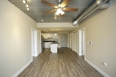 This single-floor unit blends modern finishes with industrial-inspired design elements, creating a distinctive and functional living space. The kitchen serves as a central highlight, featuring crisp white cabinetry extending to the ceiling, dark granite countertops, and a full suite of stainless steel appliances including a refrigerator, electric range, microwave, and dishwasher. A central island with a matching granite surface provides additional prep space and casual seating. Light wood-style flooring runs throughout the kitchen and entry area, adding warmth and continuity.

The bedrooms are carpeted for comfort and feature a standout architectural detail: dark-painted, corrugated metal ceilings with exposed ductwork and ceiling fans, lending an industrial loft character to the space. Large windows fill these rooms with natural light and offer views of the surrounding area.

Two bathrooms serve the unit, each finished with white cabinetry and dark granite countertops. The primary bathroom includes a wide vanity with a large mirror and a glass-enclosed shower. The secondary bathroom features a skylight, a single vanity, and a glass-enclosed shower-tub combination. Both bathrooms are finished with the same light wood-style flooring found throughout the main living areas, ensuring a cohesive aesthetic across the entire unit.