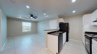 Located at 9500 S Mile One E Rd in Mercedes, Texas, this single-floor unit presents a clean, contemporary design throughout. Large-format light tile flooring runs consistently across the living spaces, contributing to a bright and cohesive aesthetic.

The kitchen is well-appointed with white cabinetry, dark granite countertops, and black appliances including a refrigerator, electric range, and dishwasher. A peninsula with an integrated sink and additional counter space separates the kitchen from the adjoining living and dining areas, creating an open, functional layout. Recessed lighting and a ceiling fan with a tray ceiling detail add character to the living space, which also benefits from a window allowing natural light to filter in.

The bedrooms feature the same tile flooring, neutral-toned walls, and tray ceilings with ceiling fans, providing a comfortable and airy feel. Each room includes window blinds for privacy and light control.

The bathroom is finished with tile flooring, a white vanity, and a tub-shower combination with built-in shelving, offering a practical and tidy space. Overall, the unit presents a well-maintained, move-in-ready interior with consistent finishes throughout.