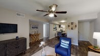 This single-floor residence offers a cohesive, thoughtfully designed layout that seamlessly connects its living and dining areas. The living room is a comfortable, inviting space featuring dark hardwood-style flooring, a ceiling fan with light fixture, and large abstract wall art that anchors the room. Natural light filters in through nearby windows, complementing the neutral tones of the walls and furnishings.

The dining area flows directly from the living room and sits adjacent to the kitchen, creating an open, functional connection between spaces. A round dining table with upholstered chairs sits beneath a flush-mount ceiling light, with bold abstract artwork adding a pop of color to the wall.

The kitchen is well-equipped with white shaker-style cabinetry, quartz countertops, a white subway tile backsplash, and black appliances including a range and dishwasher.

Two bedrooms offer restful retreats, each with closets, dark hardwood-style flooring, and serene coastal-inspired décor. The primary bedroom includes a walk-in closet for added storage convenience.

Both bathrooms are finished with white cabinetry, quartz countertops, and hardwood-style flooring. The primary bathroom features an extended vanity with a large mirror and elegant pendant lighting, while the second bathroom includes a shower-tub combination.