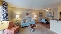 This single-floor residence offers a thoughtfully designed layout that balances comfort and functionality throughout its interconnected living spaces. The living room serves as the heart of the home, featuring plush carpeting, a textured ceiling, and generous windows dressed with patterned drapes that invite abundant natural light. The open layout flows seamlessly into a dedicated dining area, making it well-suited for both everyday living and entertaining.

The galley-style kitchen is efficiently organized with white cabinetry, dark countertops, warm hardwood-style flooring, and track lighting overhead. Black appliances, including a refrigerator and electric range, complement the clean, classic aesthetic, while a stainless steel sink adds a modern touch.

The bedroom features soft carpeting, warm neutral walls, a textured ceiling, and a window that brings in natural light. A walk-in closet provides ample storage, enhancing the room's practicality. The bathroom is finished with a full tub and shower combination, accented by a curved curtain rod and clean white surroundings.

Throughout the space, warm beige tones, layered lighting, and consistent flooring materials create a cohesive and inviting ambiance that is both comfortable and easy to navigate.