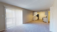 This two-floor residence offers a thoughtfully designed layout that balances open communal spaces with private retreats. The main living area is generously sized, featuring soft wall-to-wall carpeting and large sliding glass doors dressed with vertical blinds that invite natural light and provide access to the outdoors. A pendant light fixture marks the transition between the living and dining zones, creating a natural flow throughout the open-concept floor plan.

The kitchen is well-appointed with white shaker-style cabinetry, granite-look countertops, a subway tile backsplash, and wood-look vinyl flooring. Stainless steel appliances — including a refrigerator, dishwasher, and electric range — provide a modern, functional workspace. A window above the sink adds additional natural light to the kitchen area.

The bathrooms are finished with white vanity cabinetry, granite-look countertops, large mirrors, and wood-look flooring. One bathroom features a shower-tub combination, while the other offers a standalone vanity and toilet.

The bedrooms are carpeted and include ceiling fans, windows with horizontal blinds, and ample wall space. A staircase connects the two floors, and the textured ceilings are consistent throughout the space, contributing to a cohesive, comfortable feel across both levels.