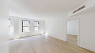 Located at 200 East Chestnut Street in Chicago's prestigious Gold Coast neighborhood, this one-bedroom, one-bathroom residence offers a well-designed layout with a clean, modern aesthetic throughout. Light hardwood floors and crisp white walls run seamlessly through the living spaces, creating a bright and airy atmosphere enhanced by abundant natural light from multiple windows framing views of the surrounding cityscape.

The spacious living room is a standout feature, boasting a row of large windows that flood the space with sunlight and provide urban views, complemented by elegant crown molding that adds a refined architectural touch. The kitchen is thoughtfully appointed with rich dark wood cabinetry, white quartz countertops, a stainless steel double-basin sink, and an eye-catching mosaic tile backsplash that adds texture and visual interest.

The generously sized primary bedroom features dual windows with city views, continuing the light hardwood flooring and crown molding details found throughout the home, with direct access to the full bathroom. The bathroom is finished with white tile, a vanity featuring a warm countertop, an undermount sink, and a large mirror. The overall ambiance of this residence is polished and inviting, offering a comfortable urban retreat in one of Chicago's most sought-after locations.