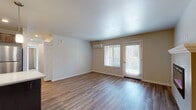 This single-floor residence at 16539 NE Halsey St in Gresham, Oregon, offers a well-designed layout with a clean, modern aesthetic throughout. The main living area is open and airy, featuring durable wood-style flooring, neutral wall tones, and a wall-mounted electric fireplace with a crisp white mantel as a central focal point. Natural light filters in through blinds-equipped windows and a glass exterior door, creating a bright and welcoming atmosphere. A wall-mounted mini-split unit provides efficient climate control.

The kitchen is a functional and stylish space outfitted with rich, dark wood cabinetry, light countertops, and a full suite of stainless steel appliances including a refrigerator, range, microwave, and dishwasher. A central island with pendant lighting above adds both prep space and visual interest, flowing seamlessly into the living areas.

The bedroom features plush carpeting and neutral walls, offering a quiet retreat. The bathrooms are well-appointed, with one featuring warm wood-style flooring, dark vanity cabinetry, and grab bars, and another with a glass-enclosed stand-up shower and wood-tone flooring. The overall space is clean, contemporary, and move-in ready.