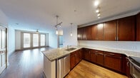 This single-floor residence offers a thoughtfully designed layout that balances functionality and style. The kitchen serves as a central highlight, featuring rich dark-wood cabinetry, granite countertops, a classic white subway tile backsplash, and a full suite of stainless steel appliances including a range, microwave, refrigerator, and dishwasher. A peninsula with an undermount sink and pendant lighting above provides both prep space and a natural transition into the open living area. Track lighting throughout the kitchen ensures excellent illumination.

The living area is bright and welcoming, with hardwood flooring and a ceiling fan overhead. A set of French doors floods the space with natural light and provides access to a balcony, offering outdoor views. Additional rooms include carpeted bedrooms, each finished with neutral tones, ceiling fans, and ample natural light from well-placed windows. A spacious walk-in closet with wire shelving offers generous storage capacity.

The bathroom continues the design language of the home with dark cabinetry, granite countertops, a wide vanity mirror, and clean tile flooring. Throughout the residence, consistent use of hardwood and carpet flooring, neutral wall tones, and quality fixtures create a cohesive and polished living environment.